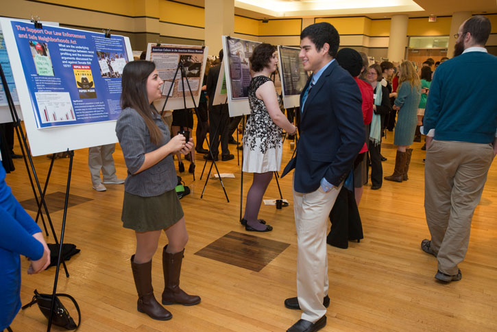 Honors College research poster display event Students chat in front of posters